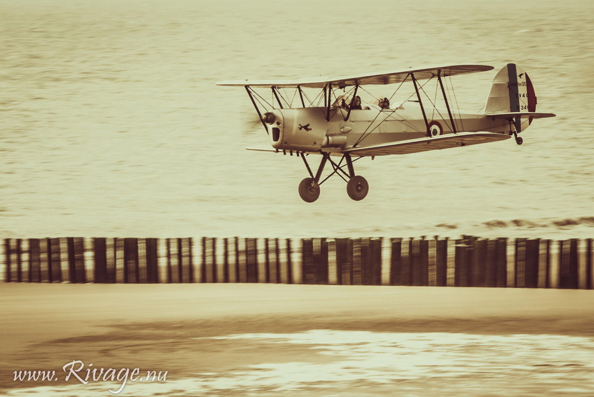 vintage dubbeldekker vliegtuig land op het strand